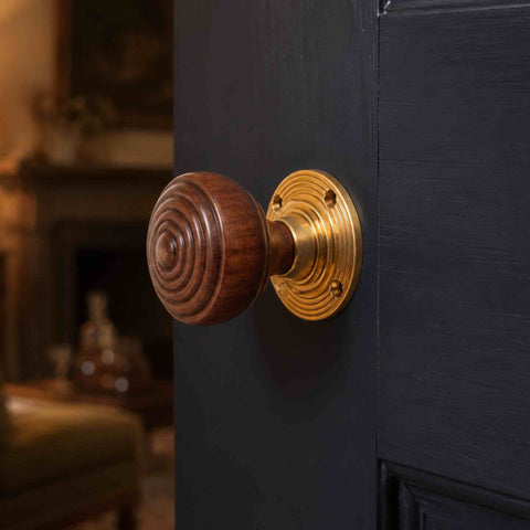 Rosewood and polished brass ringed door knob fitted to a dark painted period-style interior door