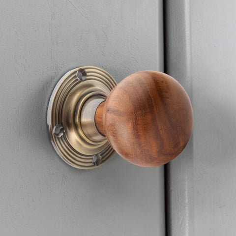 Close up of rosewood bun door knob in antique brass finish mounted on interior door