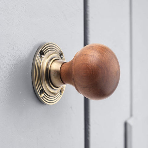 Rosewood bun door knob with antique brass reeded backplate fitted to grey door