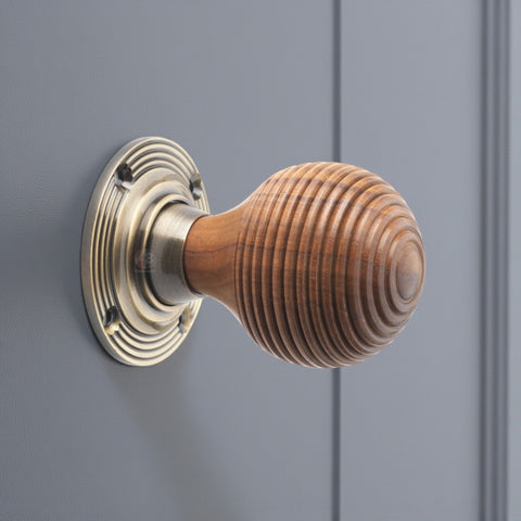 Rosewood beehive antique brass door knob fitted to grey panel door close up side view