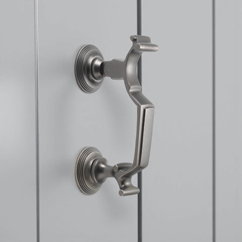 Pewter finished reeded doctor door knocker mounted on grey door, angled side view showing circular backplates and solid brass detail.