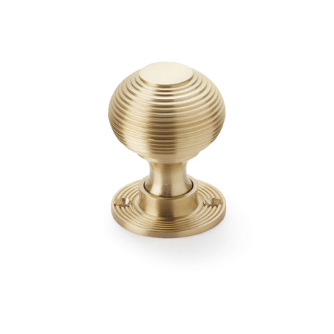 Single satin brass reeded beehive mortice door knob with circular reeded rose on white background