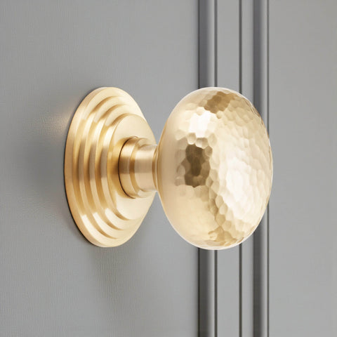 Satin brass hammered cottage centre door knob fitted to grey door showing stepped rose detail