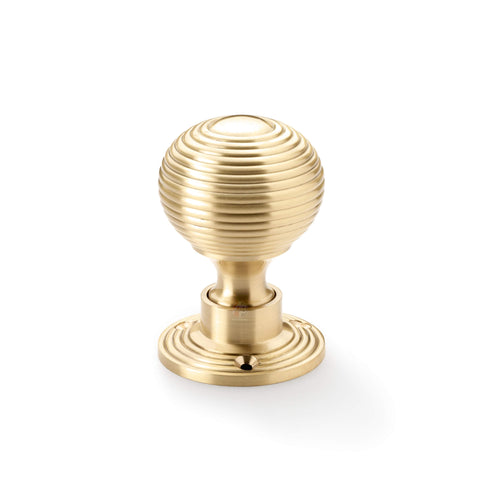 Single satin brass reeded beehive rim mortice door knob on round rose backplate.