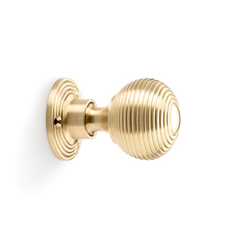 Side profile view of satin brass reeded beehive rim mortice door knob with circular backplate.