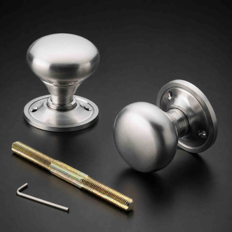 Satin chrome cottage door knob pair with round backplates, threaded spindle and Allen key on a dark background.
