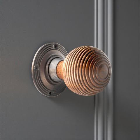 Rosewood beehive door knob installed on a grey door with a matt antique circular backplate.