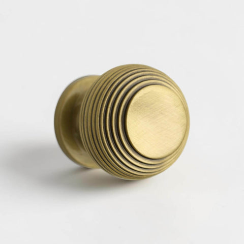 Small antique brass beehive cupboard knob front angle view showing detailed ridged beehive design.