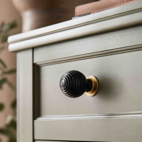 Ebonised beehive cupboard knob with unlacquered aged brass backplate fitted to a sage green painted drawer.