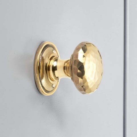 Solid aged brass hammered cupboard knob with plain backplate fitted to grey cabinet door