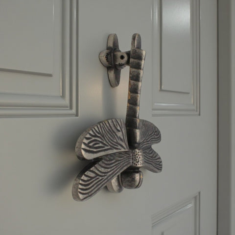 Side view of pewter dragonfly door knocker on grey door showing detailed wings.