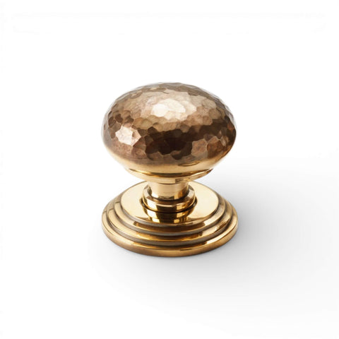 Solid brass hammered mortice door knob on stepped backplate in unlacquered aged brass finish