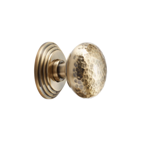 Side view of hammered solid brass mortice door knob on stepped backplate antique brass finish