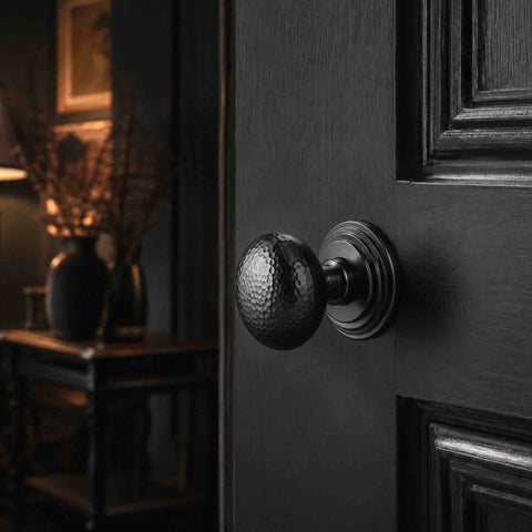 Powder Coated Black hammered mortice door knob with stepped backplate fitted to a black panelled interior door