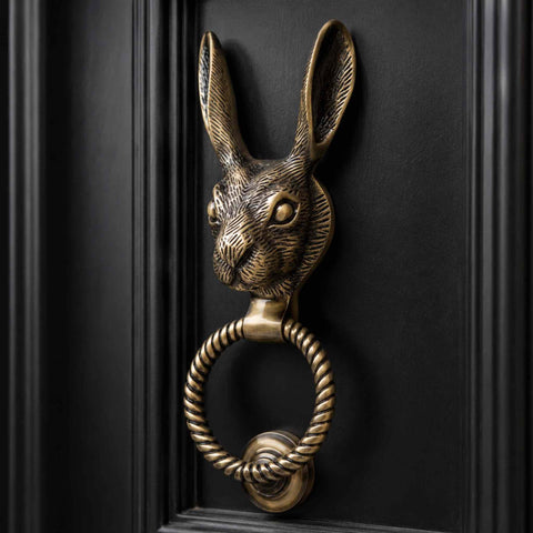Antique brass hare door knocker with reeded ring mounted on a black front door