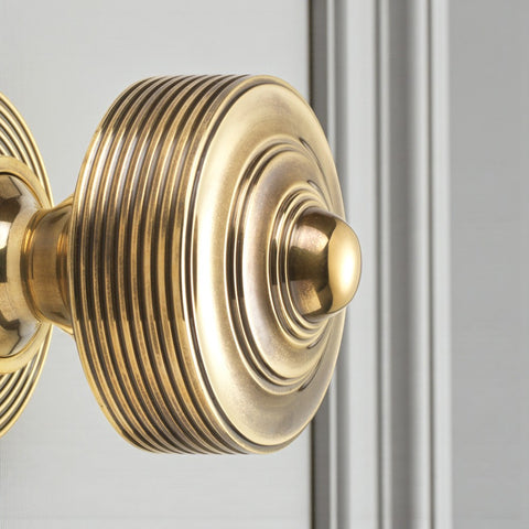 Close up of unlacquered aged brass reeded centre door knob fitted to a door, showing detailed ridged design.