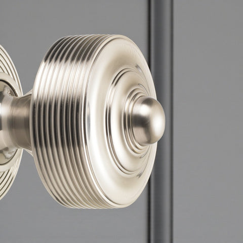 Close-up side view of satin nickel reeded centre door knob fitted to a door.