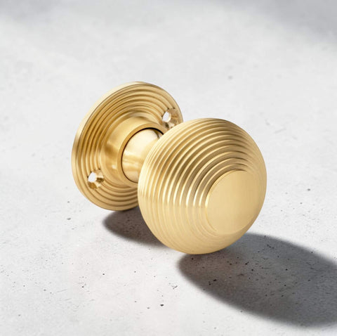 Satin brass reeded beehive door knob with circular rose backplate on light stone surface