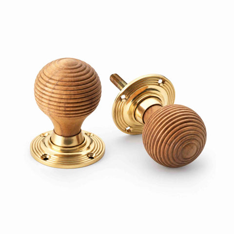 Teak beehive door knob pair showing natural wood grain and polished brass reeded backplates