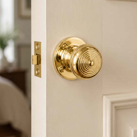 Unlacquered Polished Brass Ringed Christoph Mortice Door Knob installed on a white internal door with traditional brass latch