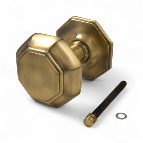 Very large antique brass octagonal centre door knob with matching backplate and fixing bolt on white background