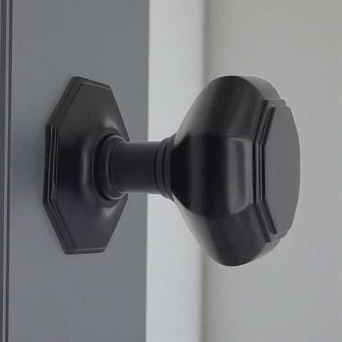 Very large powder coated black octagonal centre door knob installed on door, showing projection and scale