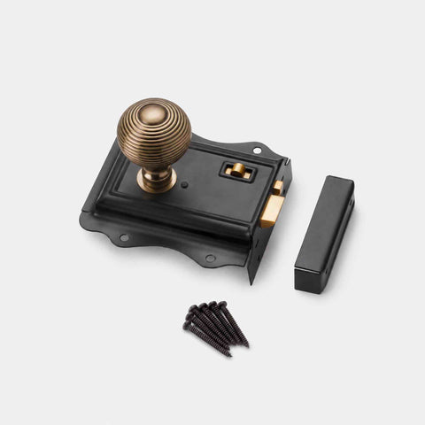 Black Olde Victorian rim lock with antique brass beehive door knob, matching keep and fixing screws displayed on a white background.
