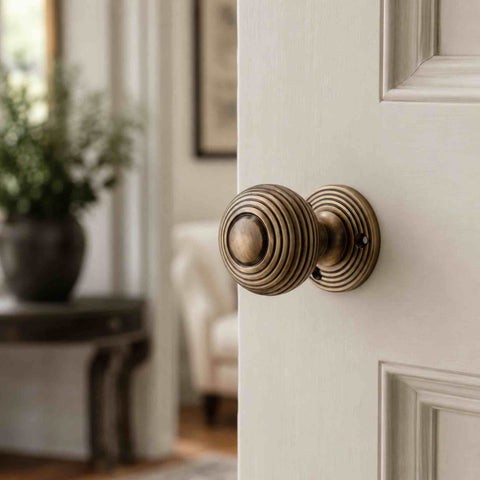 Antique brass beehive rim mortice door knob fitted to a painted interior door, showcasing the traditional reeded design.