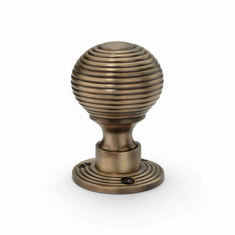 Single antique brass beehive rim mortice door knob with matching backplate, featuring a traditional reeded design and antique brass finish.